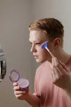 A Vertical Close-up of a Man Applying Highlighter with Brush Looking into Mirror Stock Photos