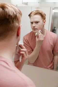 A Vertical Close-up of a Man Removing Makeup with Wipe in Front of Mirror Stock Photos