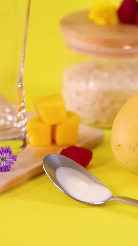 Vertical Close Up of Mango Cubes and Raspberries on Yellow Background Stock Footage 329740910