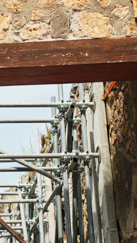 Vertical close-up of metal scaffolding and wooden bracing supporting ancient Vidéo 336472602