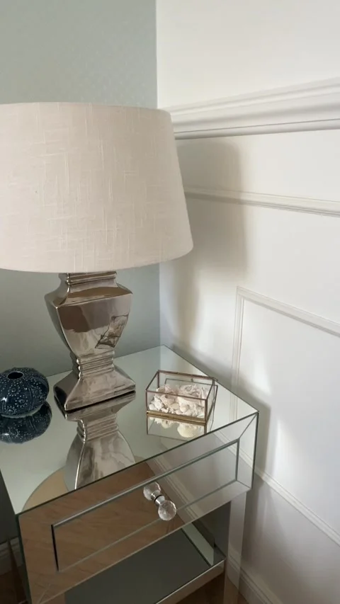 Vertical close up of mirrored nightstand with table lamp and luxury wall molding Video stock 346486285