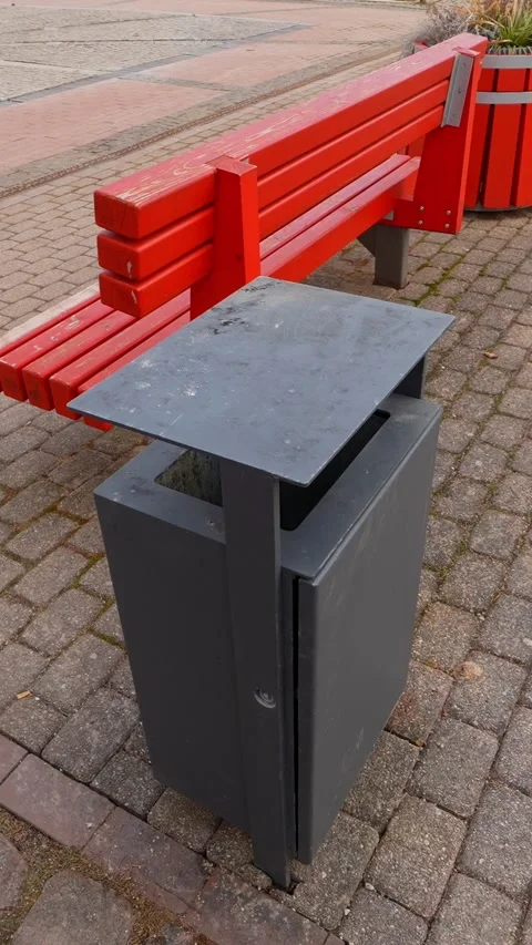Vertical close-up of a modern black trash bin beside bright red benches in Stockbeeldmateriaal 333655844