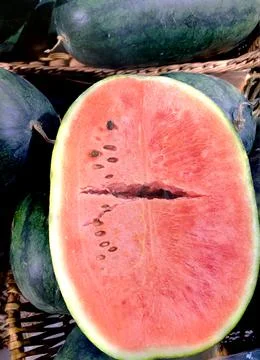 Vertical close-up one red cut watermelons wooden baskets. Stockfoto's