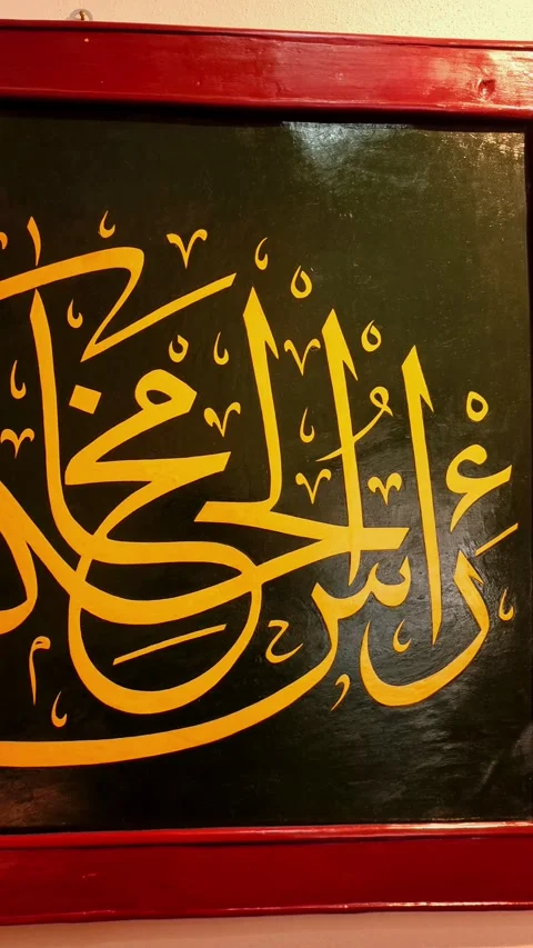Vertical close-up panning shot of golden Arabic calligraphy "Ras al-Hikma" on a Vídeos de archivo 334029393
