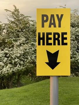 Vertical close up of pay here yellow sign with arrow outdoors Stock Photos
