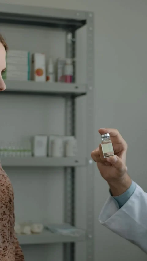 Vertical of Close-up of pharmacist, offering a COVID-19 vaccine to female client Stock Footage 276927749
