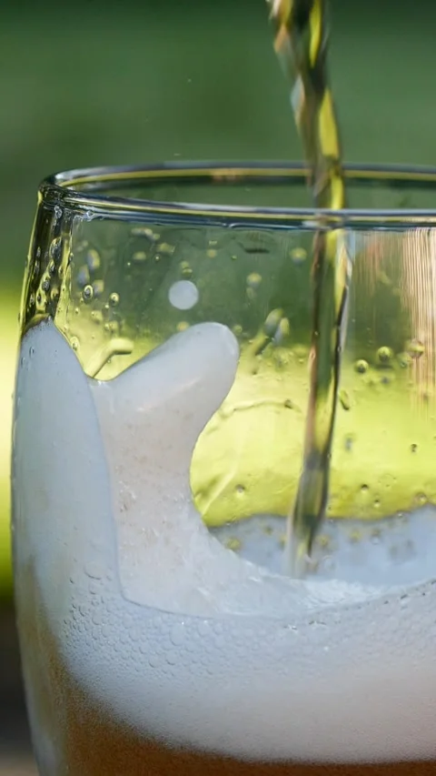 Vertical close-up of pouring beer with foam and bubbles in glass in slow motion Stock Footage 264013210