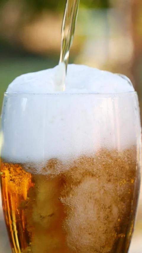 Vertical close-up of pouring beer with foam and bubbles in glass in slow motion Stock Footage 264802442