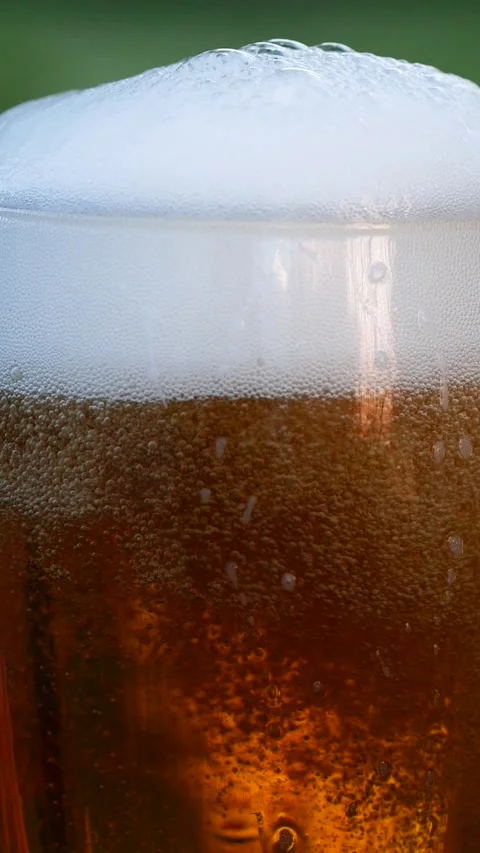 Vertical close-up of pouring beer with foam and bubbles in glass in slow motion Stock Footage 265539513