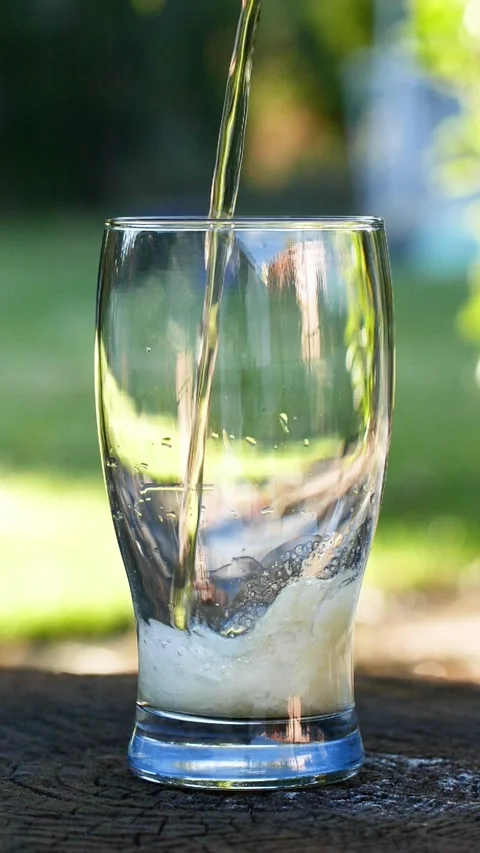 Vertical close-up of pouring beer with foam and bubbles in glass in slow motion Stock Footage 266385282