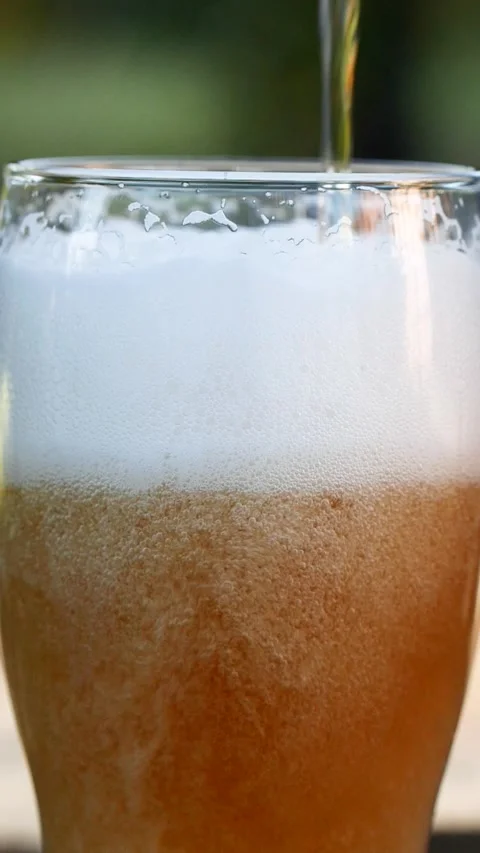 Vertical close-up of pouring beer with foam and bubbles in glass in slow motion Stock Footage 269296940