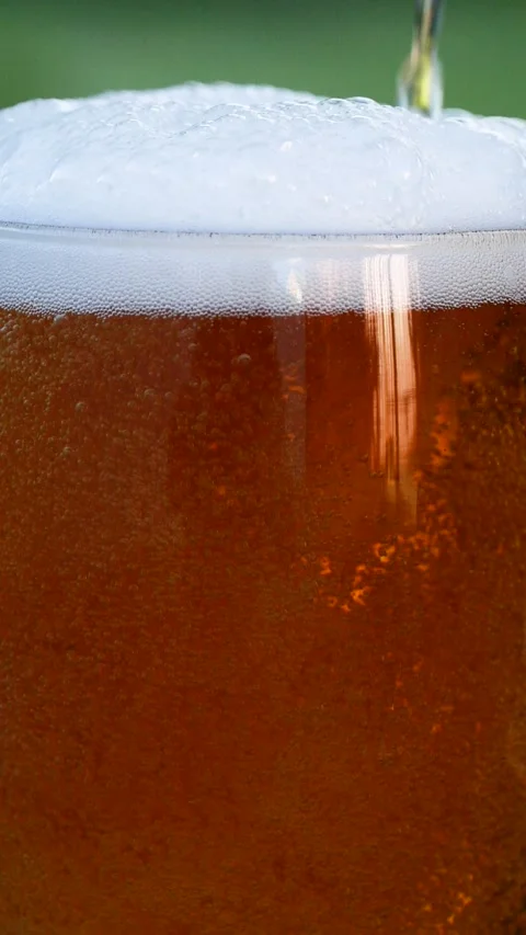 Vertical close-up of pouring beer with foam and bubbles in glass in slow motion Stock Footage 270205206