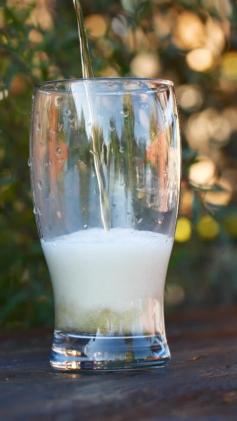 Vertical close-up of pouring beer with foam and bubbles in glass in slow motion Stock Footage 271022197