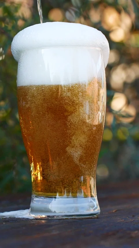 Vertical close-up of pouring beer with foam and bubbles in glass in slow motion Stock Footage 273016861