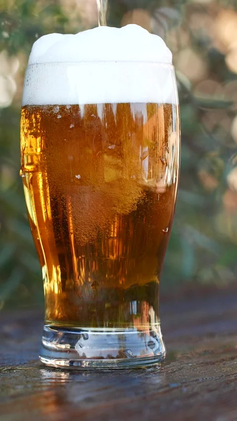 Vertical close-up of pouring beer with foam and bubbles in glass in slow motion Stock Footage 274330260
