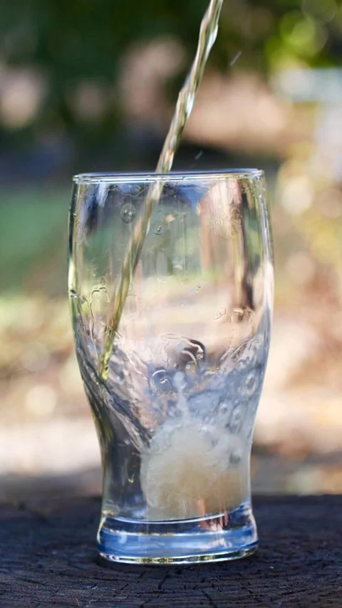 Vertical close-up of pouring beer with foam and bubbles in glass in slow motion Video stock 274784723