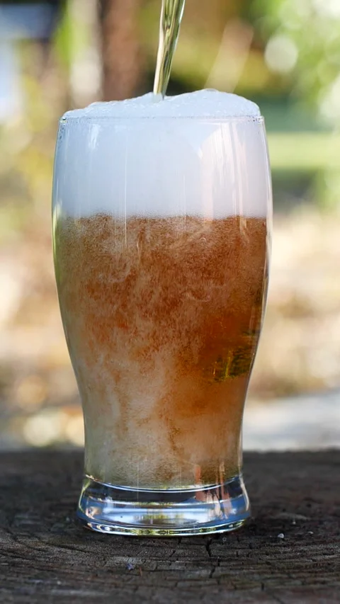 Vertical close-up of pouring beer with foam and bubbles in glass in slow motion Stock Footage 275479352
