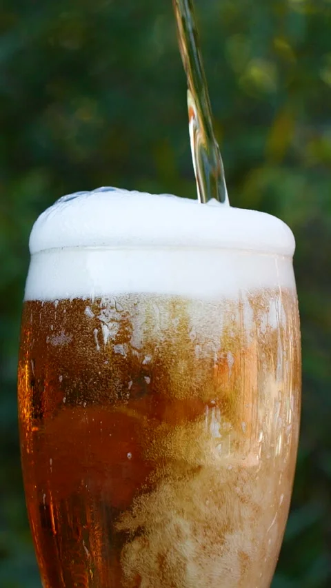 Vertical close-up of pouring beer with foam and bubbles in glass in slow motion Stock Footage 277018629
