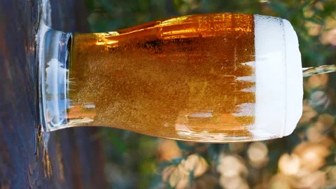 Vertical close-up of pouring beer with foam and bubbles in glass in slow motion Stock Footage 279874647
