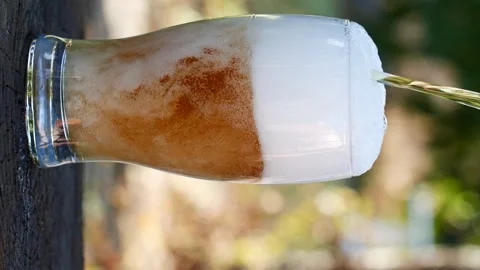 Vertical close-up of pouring beer with foam and bubbles in glass in slow motion Stockbeeldmateriaal 280738722