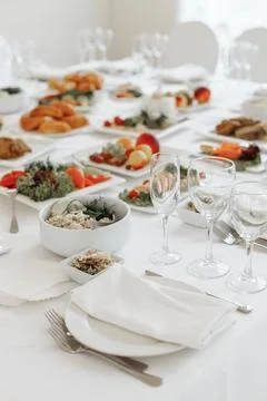 Vertical close-up of a pristine white place setting with wine glasses, napkin Stock Photos