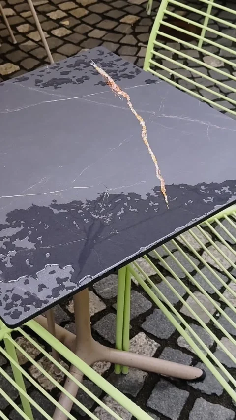 Vertical close-up of a rain-wet café table with a long scratched surface Vídeo Stock 342488423