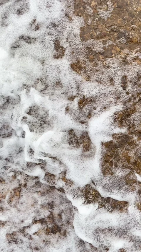 Vertical close up of rushing water with white foam over a rocky riverbed. Stock Footage 346012893
