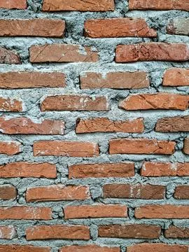 Vertical close up of rustic red brick wall with rough mortar texture Stock Photos