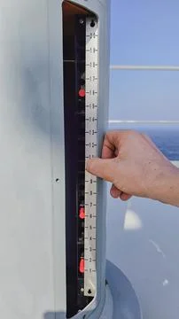 Vertical close up of a sailor hand adjusting a metallic measurement scale i.. Foto stock