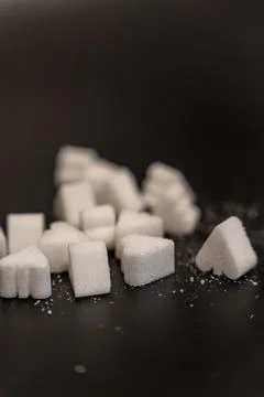 Vertical close up of scattered sugar cubes and heart shaped pieces with fine Stock Photos