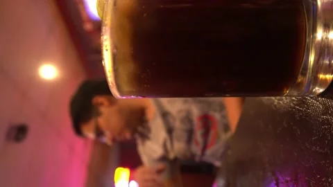 Vertical close-up shot of cuba libre with the background of a man drinking beer Stock Footage 196736554