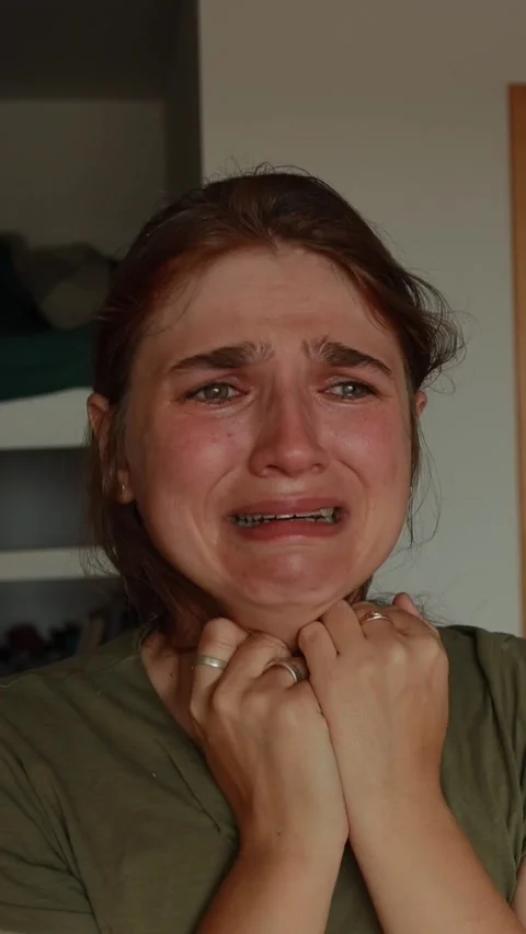Vertical close-up shot of a distressed young woman crying and clutching her.. Stock Footage 346221513