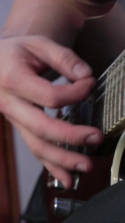 Vertical close up shot of a guitarist's right hand fingerpicking strings near Stock Footage 345211284