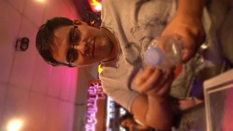 Vertical close-up shot of a man removing the label from a plastic water bottle i Vidéo 196737150