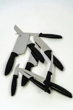 Vertical close-up shot of sharp kitchen knives placed on a white background 库存照片
