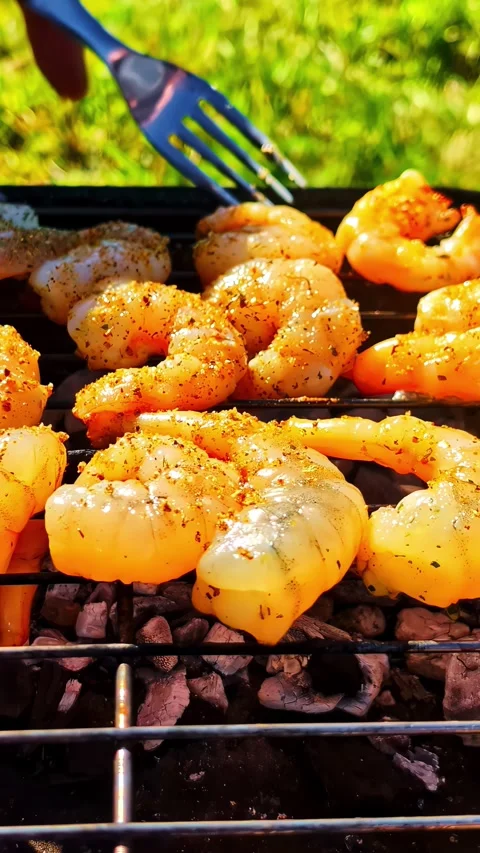 Vertical close-up of shrimp and prawns grilling over charcoal, with a fork Stock Footage 336661553