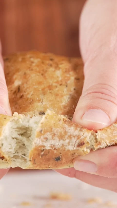 Vertical close-up slow motion of hands tearing whole grain bun with spinach.. Vídeos de archivo 312169497