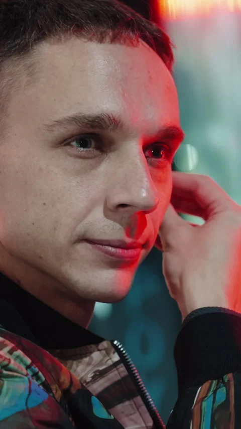 Vertical close-up slowmo of a mans putting earphones in the ears, streetlights Vídeo Stock 321331899