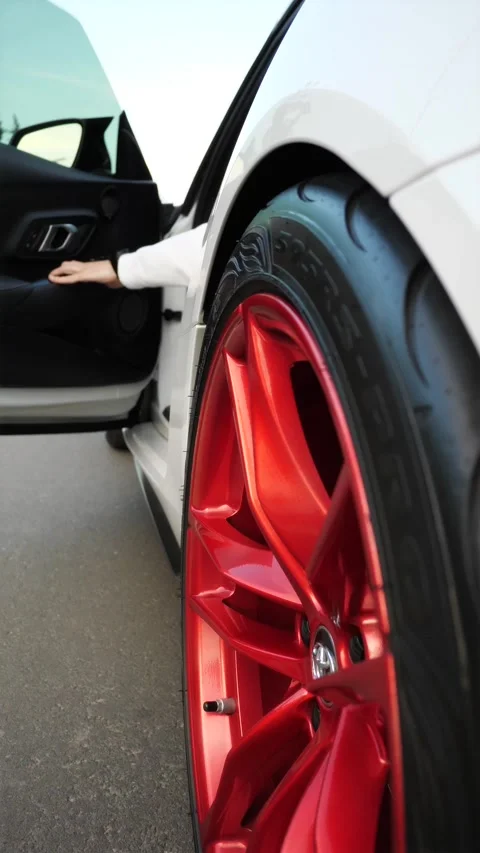 Vertical close up of spinning red custom alloy wheel on sports car Stock Footage 337615662