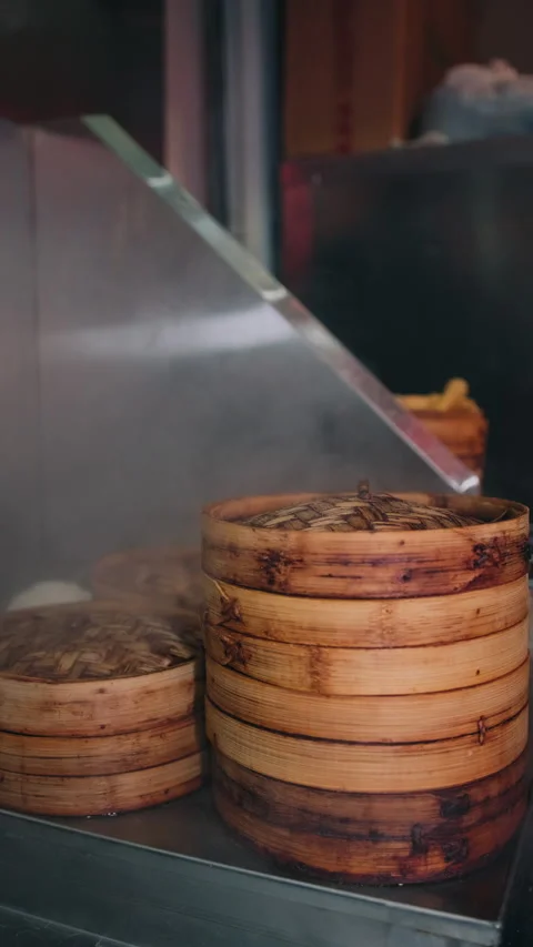 Vertical close-up of stacked bamboo steamers with steam rising in restaurant Stock Footage 333894730