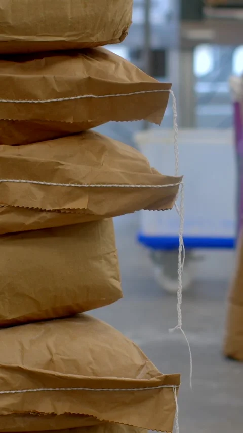 Vertical close-up of stacked kraft sacks with hanging twine in bakery storage Видео 344575591