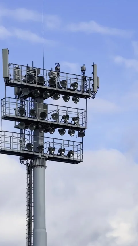 Vertical close-up of a stadium floodlight tower with telecom antennas, safety Stock Footage 340919802