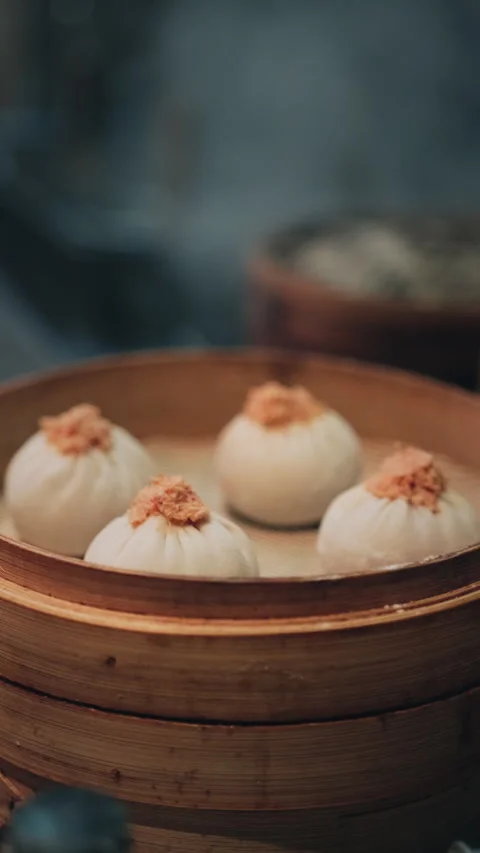 Vertical close-up of steamed Chinese buns with orange topping in bamboo steamer Stock Footage 333895190