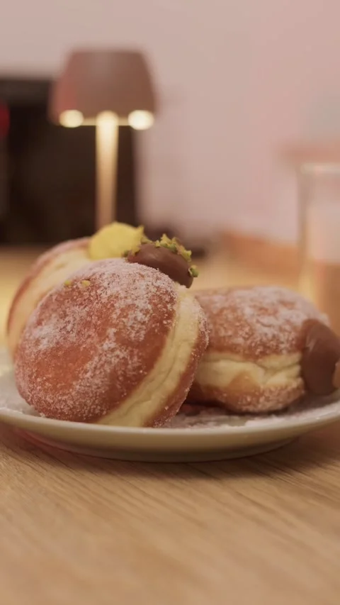 Vertical close-up of sugar-coated filled doughnuts with chocolate and pistachios Stock Footage 321020034