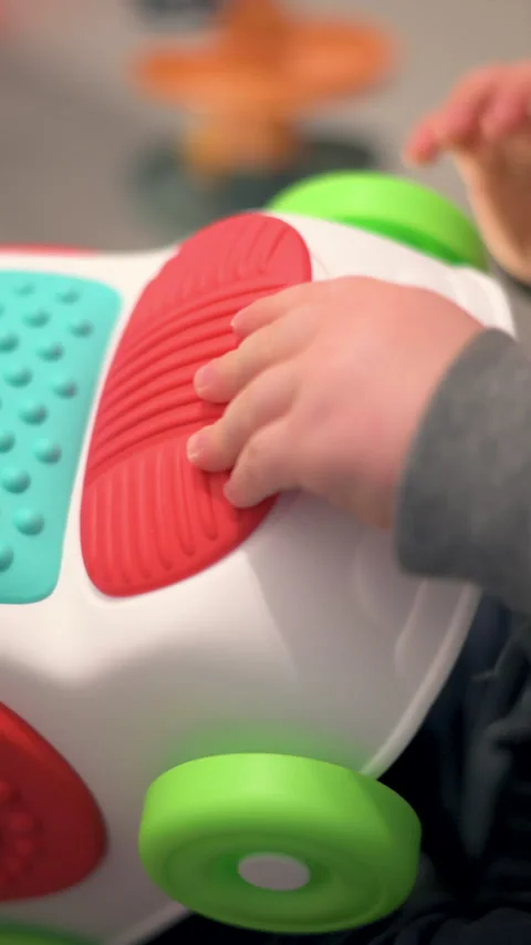 Vertical Close-Up Toddler Hand Touching Sensory Buttons On Colorful Toy Car Stock Footage 330967686