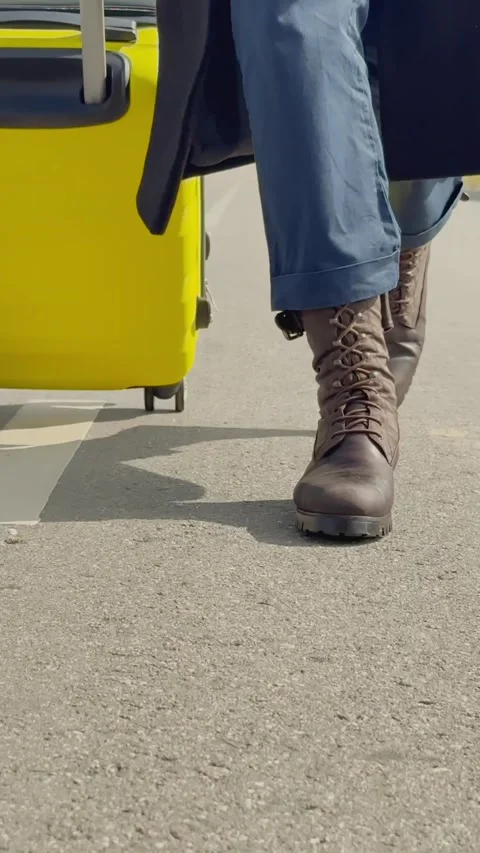 Vertical close-up of unrecognizable womans feet, walking with yellow suitcase Stock Footage 313733641