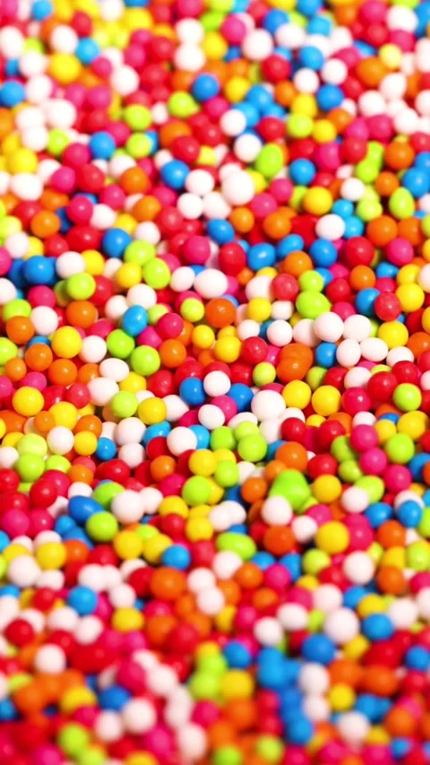 Vertical Close Up of Vibrant Rainbow Sprinkles Pouring and Settling Stock Footage 326088693
