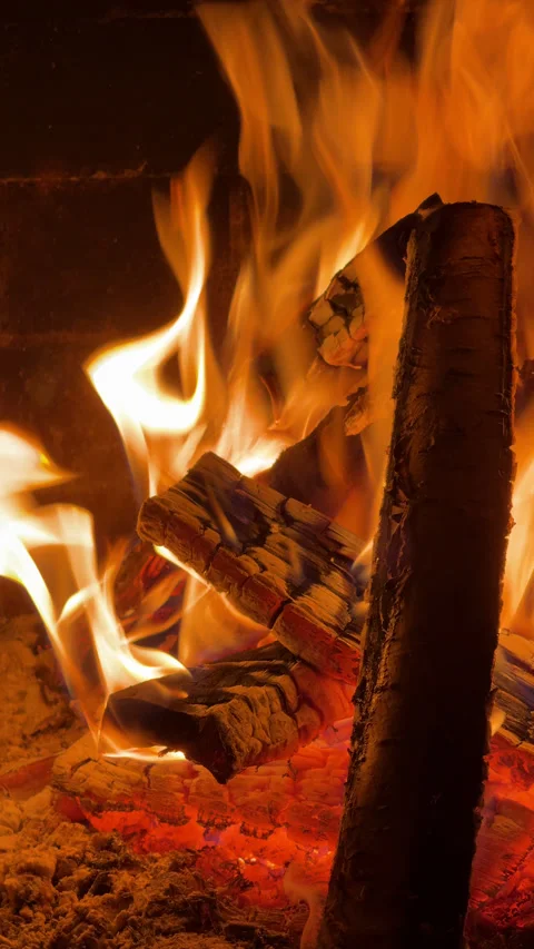 Vertical close-up video of a burning fireplace with crackling wooden logs. Warm  Stock Footage 325745797