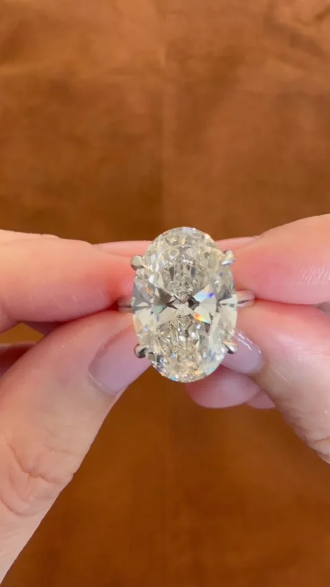 Vertical close up video displaying the front view of an oval engagement ring. Stock Footage 314786717