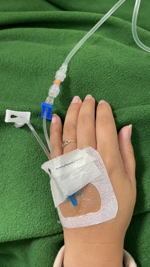 Vertical close-up video of a woman's hand receiving an intravenous (IV) drip. Stock Footage 297675443